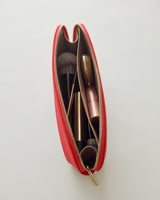 Makeup brushes and a lipstick inside an open cosmetic pouch.