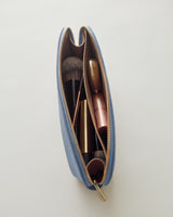 Makeup bag filled with brushes and lipstick viewed from above.