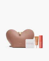 Heart-shaped pouch with three cosmetics tubes and compact case displayed.
