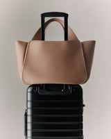 Tote bag placed on a rolling suitcase handle.
