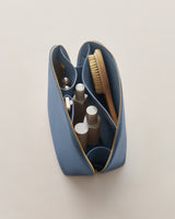 Open toiletry bag with bottles, brush, and small items inside.