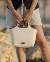Person holding a tote bag with both hands in front of a rocky background.