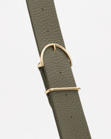 Close-up of a textured belt with a gold buckle and loop.