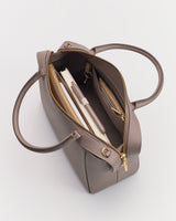 Open handbag with pen, notebook, and wallet inside, lying on a flat surface.