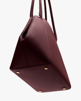 A handbag with metal feet and two handles.