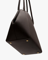 Tote bag with gold studs on the bottom, shown from a side angle.
