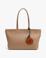Tote bag with flower accessory hanging from handle.
