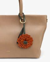 Handbag with a floral accessory attached to the handle