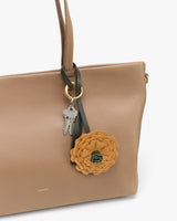 Handbag with a flower keychain and keys attached.