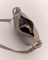 Open handbag with keys, folded sunglasses, and bottles inside