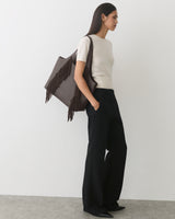 Woman in a tee and pants carrying a fringe tote bag