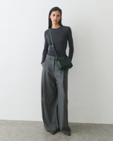 Person wearing long-sleeve top, wide-leg pants, and shoulder bag.