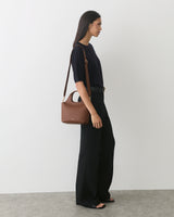 Person in a top and pants carrying a shoulder bag.