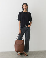 Person in casual outfit holding a large travel bag.
