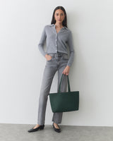 Person wearing a shirt and jeans holds a tote bag.