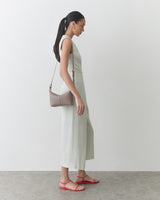 Person wearing sleeveless dress with shoulder bag and sandals standing on concrete floor