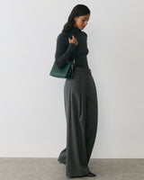 Person in a turtleneck and wide-leg pants holding a shoulder bag.