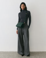 Person wearing turtleneck and wide-leg pants with a crossbody bag.