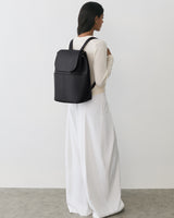 Person wearing a long dress and carrying a backpack, facing sideways.