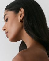Person wearing geometric earrings, looking to the left.