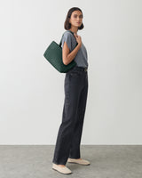 Person in casual outfit holding a shoulder bag.