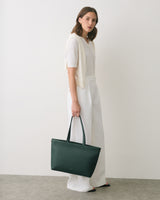 Person holding a handbag, wearing a short sleeve shirt and long pants.