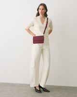 Person wearing a long-sleeve shirt, wide-leg pants, belt bag, and heeled shoes.