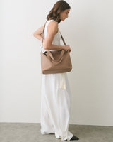 Woman in sleeveless top and long skirt holding a shoulder bag