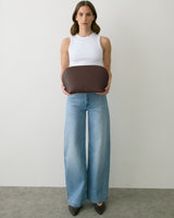Person holding a rounded bag, wearing a sleeveless top and wide-leg jeans.