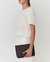 Person holding a rectangular clutch bag.
