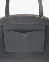 Leather handbag close-up with open pocket and brand logo.