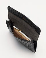 Open croc-embossed leather clutch with a wallet and phone inside.