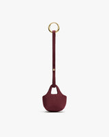 Small textured pouch with a long strap and a round metal ring at the top.