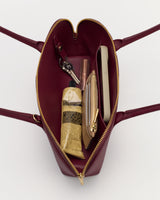 Open handbag with visible items like keys, a phone, a tube, and a small pouch inside.