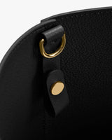 Close-up of a bag's inner D-ring and button detail.