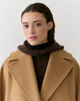 Person wearing a cape over a sweater with a hood.