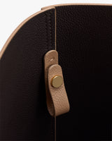 Close-up of a bag interior with a leather strap and metal button.