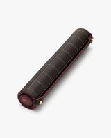 Rolled picnic blanket with grid pattern and leather strap closure.