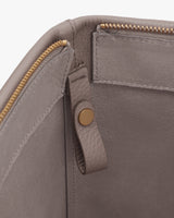 Open leather bag with zipper and button detail inside.