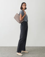 Person in casual outfit holds a handbag on shoulder.