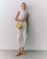 Person standing with small handbag and wearing sandals.