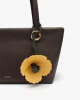 Handbag with a flower charm attached to the strap.