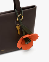 Handbag with flower and keychain attached.