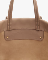 Close-up of a bag with dual handles and rivet details.