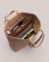 Open tote bag with notebooks, phone, and small items inside.