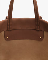 Close-up of a handbag with two handles and gold button accents.