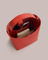 Open handbag with visible items inside including a wallet and sunglasses.