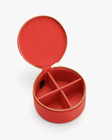 Round jewelry case with open lid showing divided compartments.