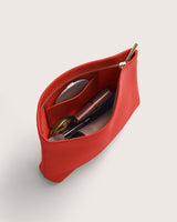 Open cosmetic pouch with makeup and accessories inside.