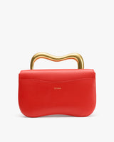 Handbag with curved handle on top.